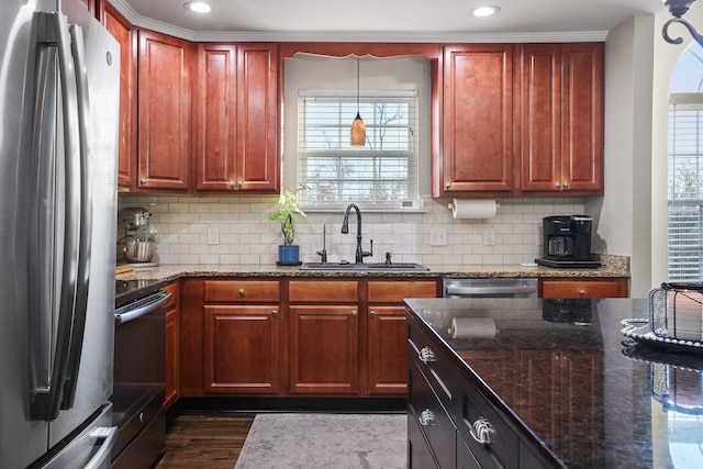 kitchen featuring a healthy amount of sunlight, dark stone countertops, sink, and appliances with stainless steel finishes