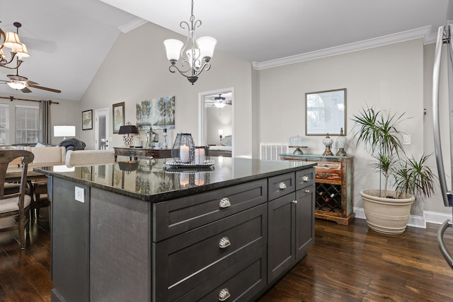 kitchen featuring dark hardwood / wood-style floors, pendant lighting, dark stone counters, a kitchen island, and ornamental molding