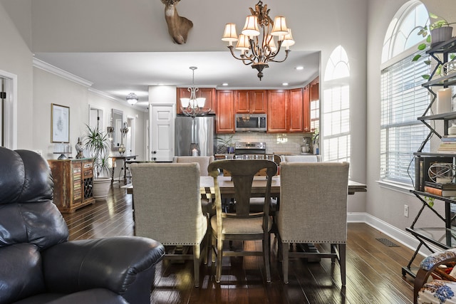 dining room with dark hardwood / wood-style floors, crown molding, and an inviting chandelier