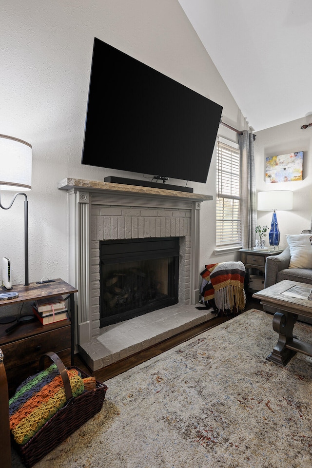 living room with hardwood / wood-style floors, lofted ceiling, and a fireplace