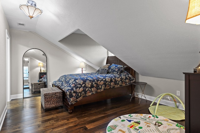 bedroom featuring a textured ceiling, dark hardwood / wood-style flooring, and vaulted ceiling