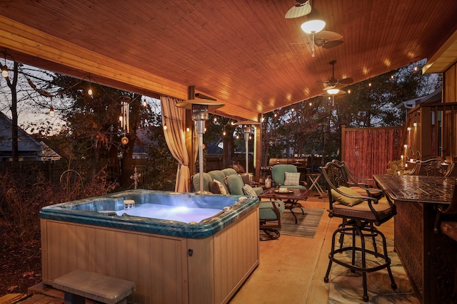 patio terrace at dusk featuring ceiling fan and a hot tub