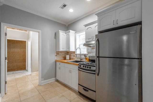 kitchen with white cabinetry, sink, stainless steel appliances, butcher block countertops, and light tile patterned flooring