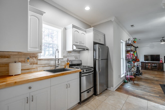 kitchen with wood counters, appliances with stainless steel finishes, sink, light hardwood / wood-style flooring, and white cabinets