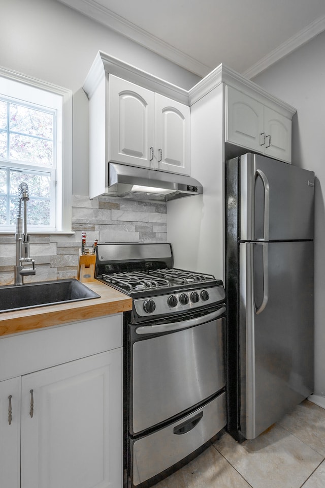 kitchen featuring backsplash, stainless steel appliances, sink, light tile patterned floors, and white cabinets