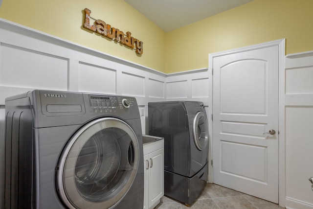 laundry room with cabinets, light tile patterned floors, and washing machine and clothes dryer