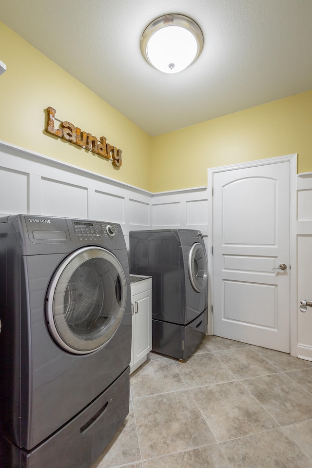 laundry area featuring cabinets, light tile patterned floors, and washing machine and dryer