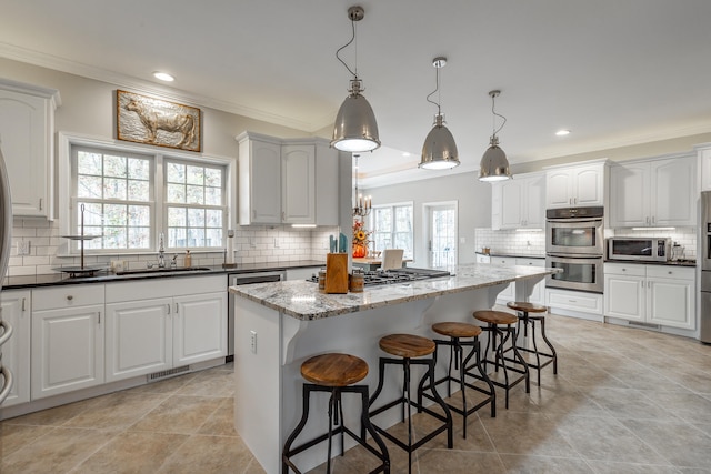 kitchen featuring stainless steel appliances, sink, decorative light fixtures, dark stone countertops, and white cabinets