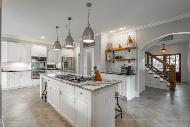 kitchen with white cabinets, a breakfast bar area, dark stone countertops, a kitchen island, and stainless steel appliances