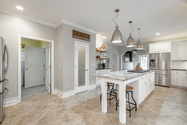 kitchen featuring tasteful backsplash, decorative light fixtures, a kitchen island, white cabinetry, and stainless steel appliances