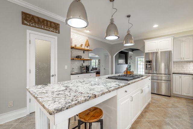 kitchen with decorative backsplash, white cabinetry, a kitchen island, and appliances with stainless steel finishes