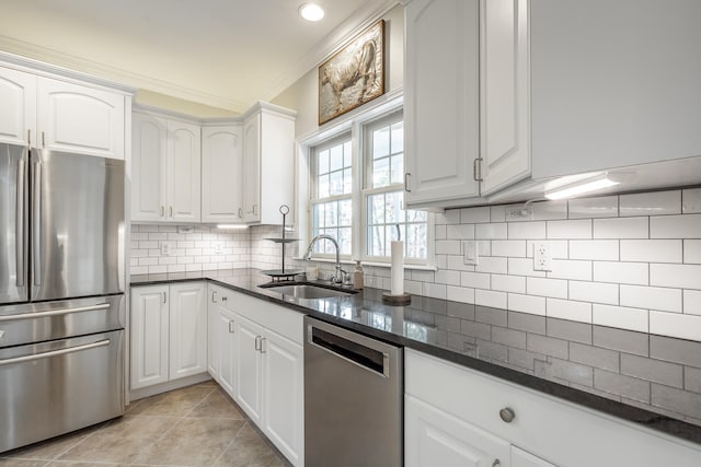 kitchen featuring appliances with stainless steel finishes, tasteful backsplash, dark stone counters, sink, and white cabinetry