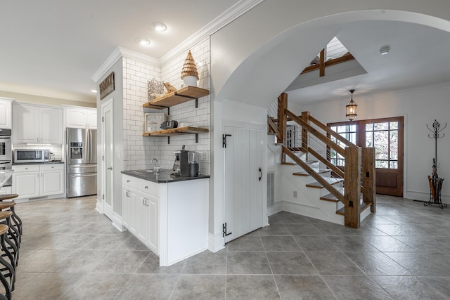 kitchen with white cabinets, decorative backsplash, stainless steel appliances, and crown molding