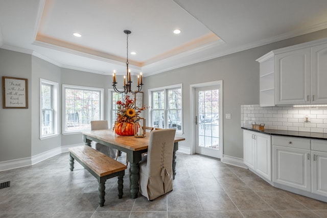 tiled dining room with a raised ceiling, a wealth of natural light, and a chandelier