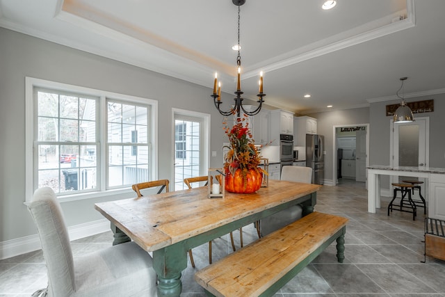 tiled dining space featuring a notable chandelier, a raised ceiling, and crown molding