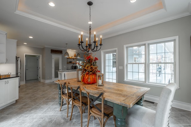 tiled dining area with a notable chandelier, a raised ceiling, and crown molding