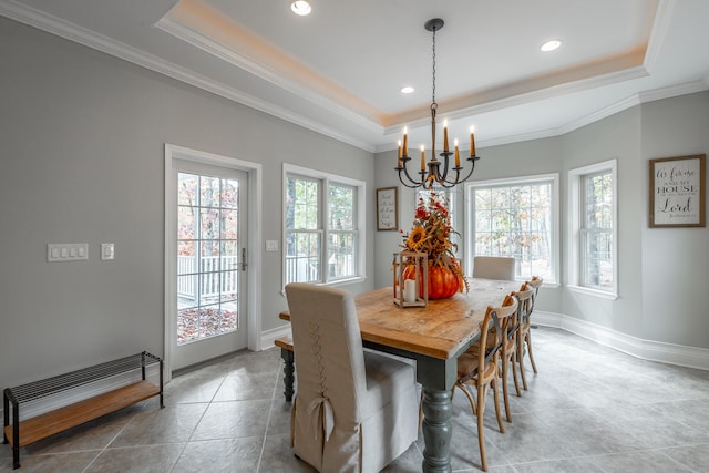 tiled dining room featuring a chandelier, a tray ceiling, and ornamental molding