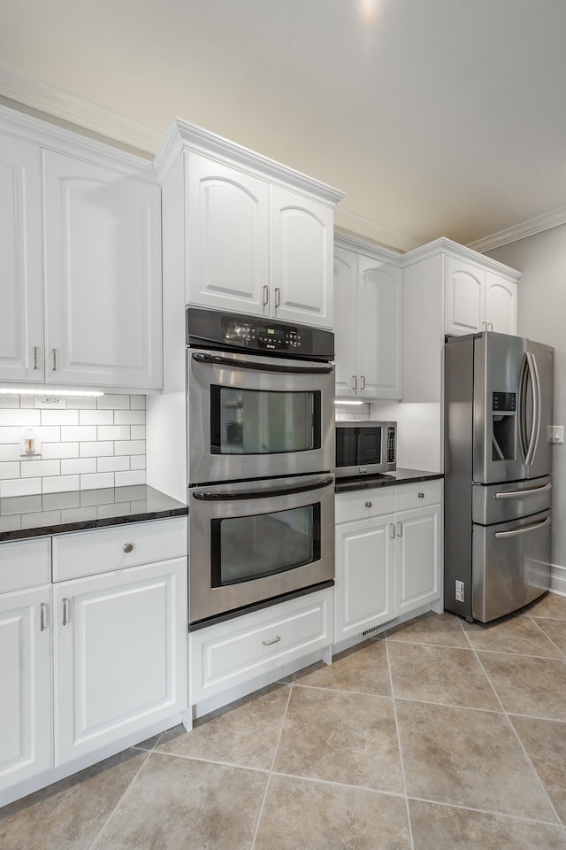 kitchen featuring light tile patterned floors, white cabinetry, backsplash, and appliances with stainless steel finishes