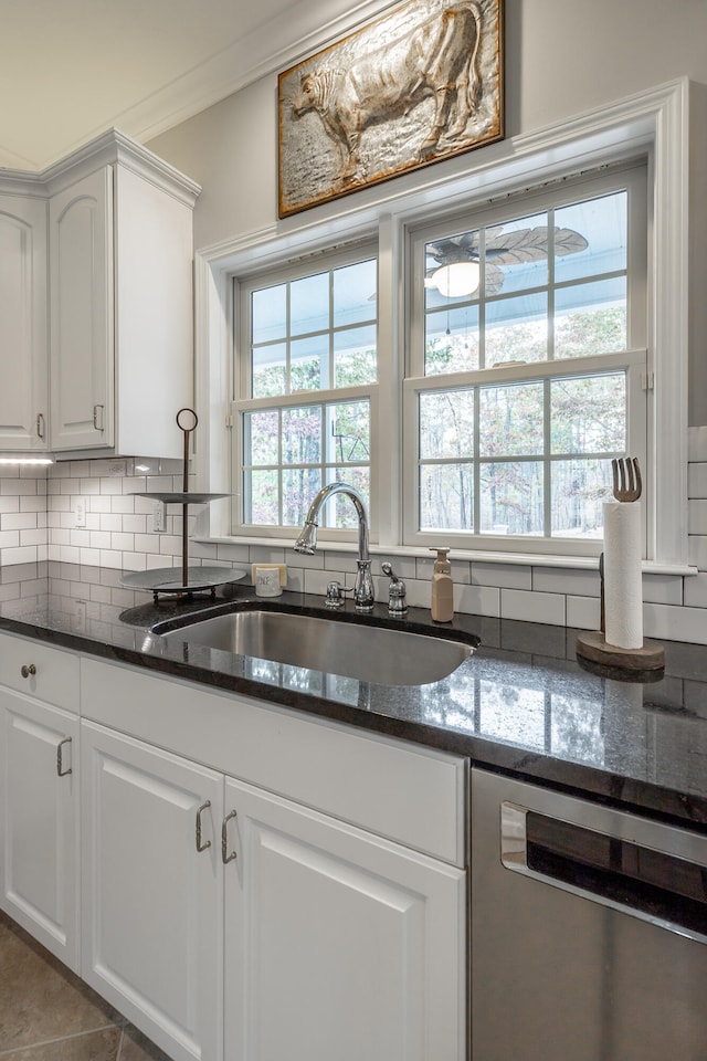 kitchen with sink, stainless steel dishwasher, backsplash, dark stone countertops, and white cabinets