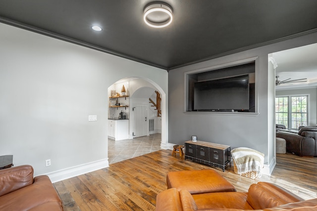 living room with ceiling fan, light wood-type flooring, and ornamental molding