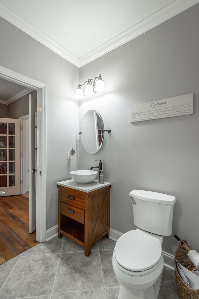 bathroom featuring wood-type flooring, vanity, toilet, and crown molding