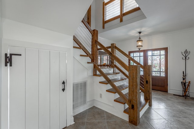 stairs featuring a chandelier, tile patterned flooring, and crown molding