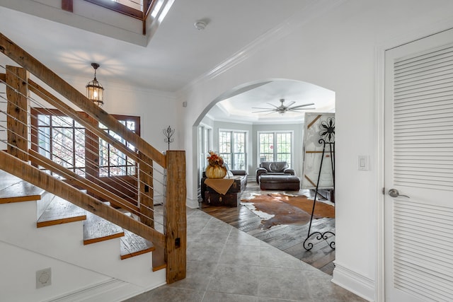 stairs featuring wood-type flooring, ceiling fan, and crown molding