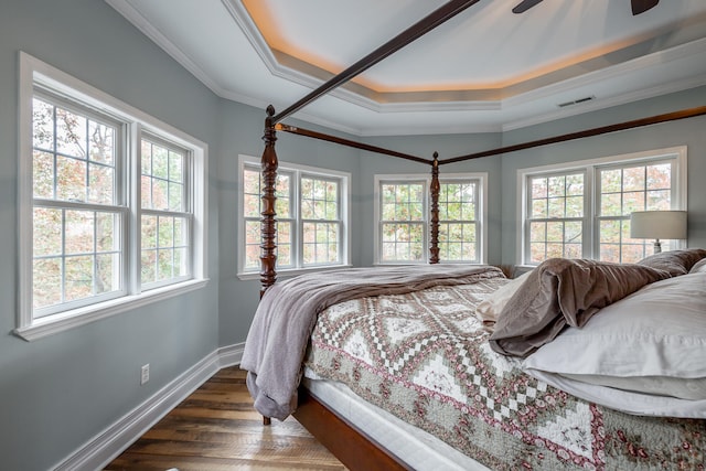 bedroom with ceiling fan, a raised ceiling, ornamental molding, and dark wood-type flooring