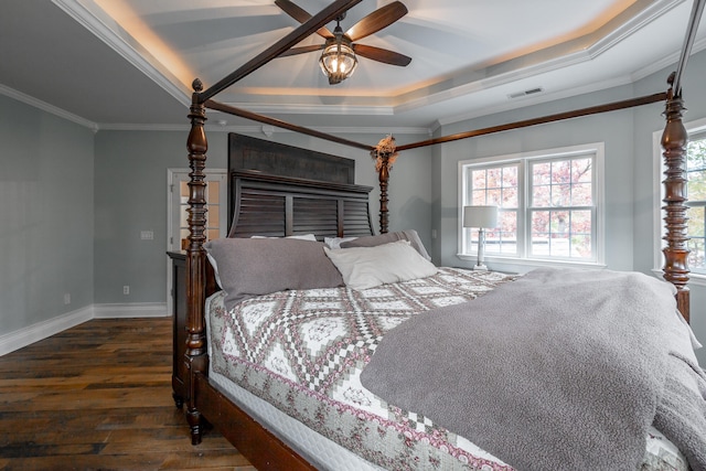 bedroom with a raised ceiling, crown molding, ceiling fan, and dark wood-type flooring