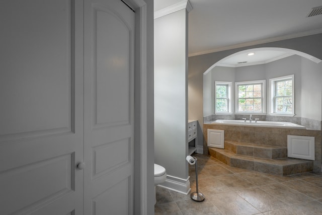 bathroom featuring tile patterned floors, toilet, a relaxing tiled tub, and ornamental molding