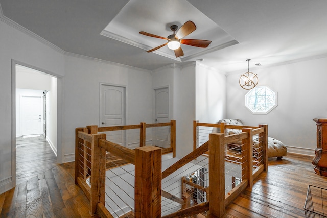 hall featuring an inviting chandelier, dark hardwood / wood-style floors, a raised ceiling, and crown molding