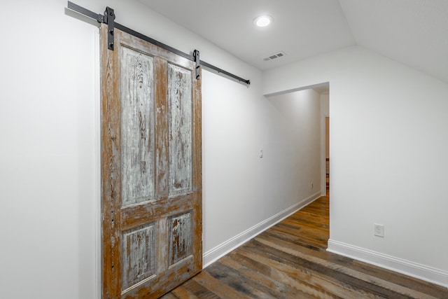 hall with a barn door, dark hardwood / wood-style flooring, and lofted ceiling