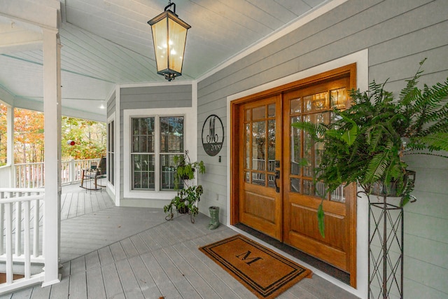 property entrance with covered porch and french doors