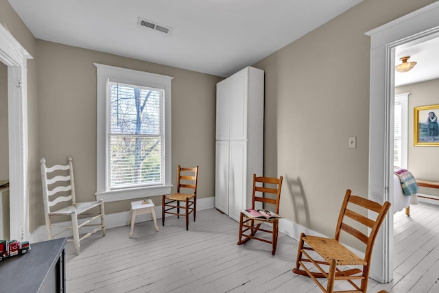 living area with a wealth of natural light and light hardwood / wood-style floors