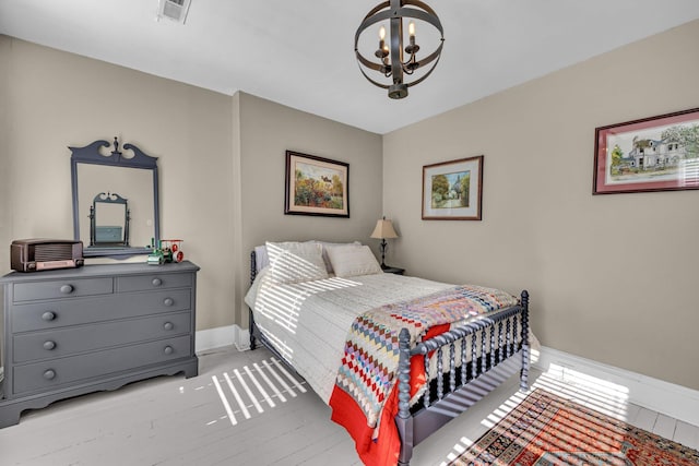 bedroom featuring light wood-type flooring and an inviting chandelier