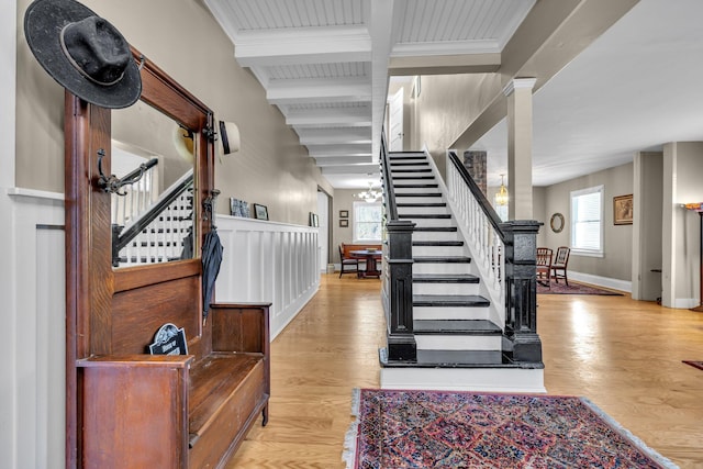 foyer entrance with beam ceiling, light hardwood / wood-style flooring, and a notable chandelier