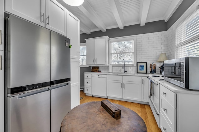 kitchen with white cabinets, sink, stainless steel appliances, and a wealth of natural light