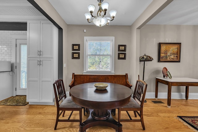 dining room with light hardwood / wood-style floors and an inviting chandelier