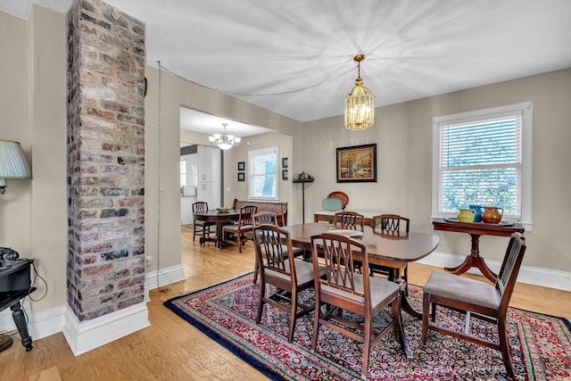 dining room featuring light wood-type flooring, plenty of natural light, and a notable chandelier