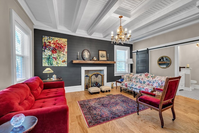 living room featuring hardwood / wood-style floors, a barn door, ornamental molding, beam ceiling, and a chandelier