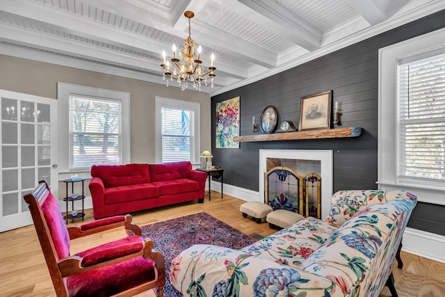 living room with beam ceiling, crown molding, wood-type flooring, and a notable chandelier