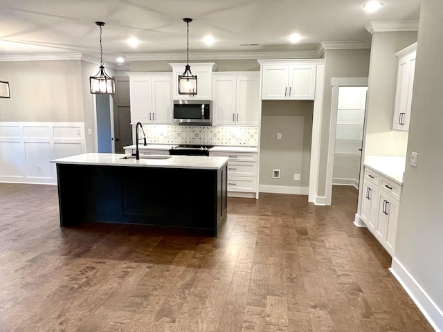 kitchen with white cabinets, a kitchen island with sink, and hanging light fixtures