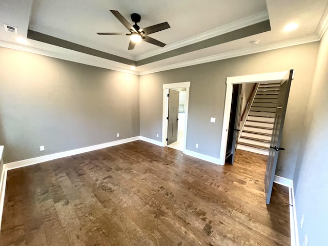 unfurnished bedroom featuring ceiling fan, ornamental molding, dark wood-type flooring, and a tray ceiling