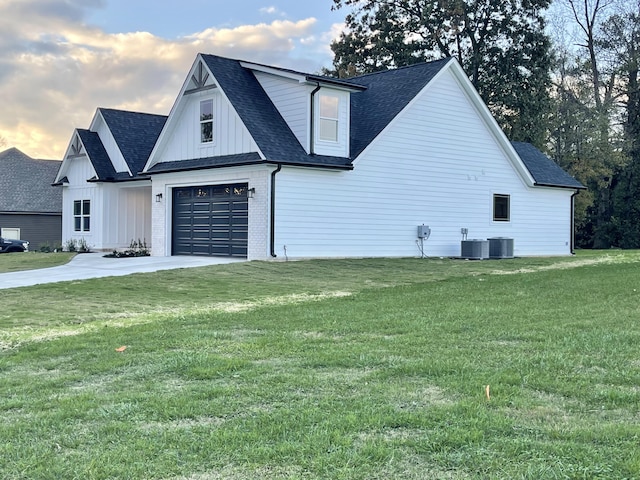 property exterior at dusk with a garage, a yard, and central air condition unit