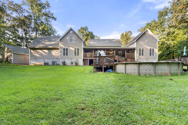 rear view of property featuring a lawn, a sunroom, and a swimming pool side deck