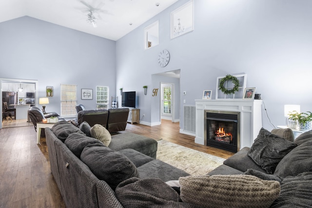 living room with ceiling fan, high vaulted ceiling, and hardwood / wood-style flooring