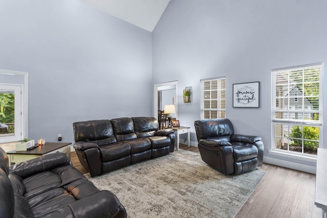 living room with plenty of natural light, wood-type flooring, and high vaulted ceiling