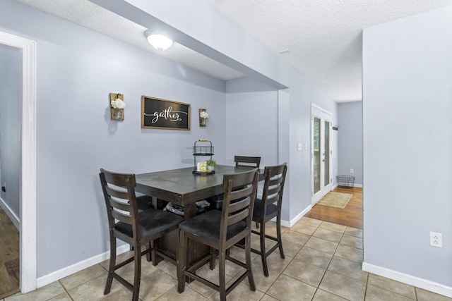 dining room with light wood-type flooring and a textured ceiling