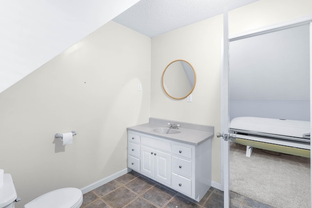 bathroom with vanity, toilet, lofted ceiling, and a textured ceiling