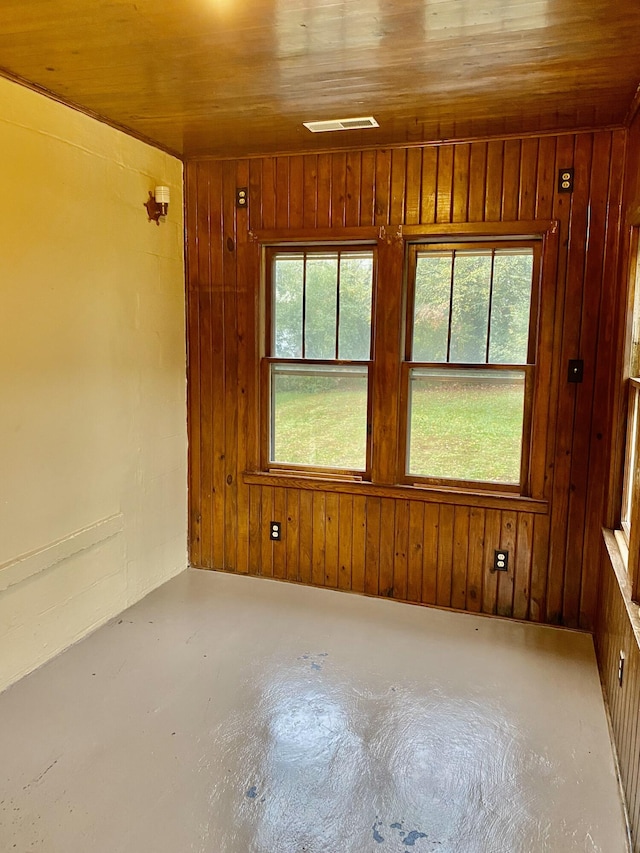 empty room with wood walls, wooden ceiling, and concrete floors